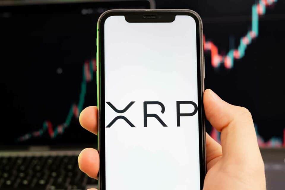 XRP-Logo auf Smartphone mit bullishem Chart im Hintergrund