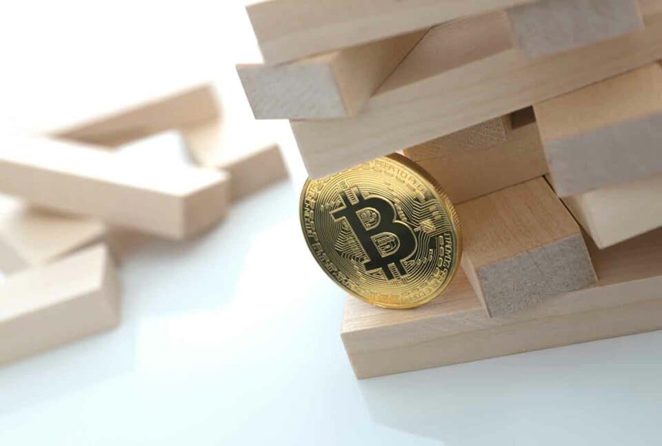Bitcoin Münze als wackeliges Fundament in einem Stapel Bauklötze