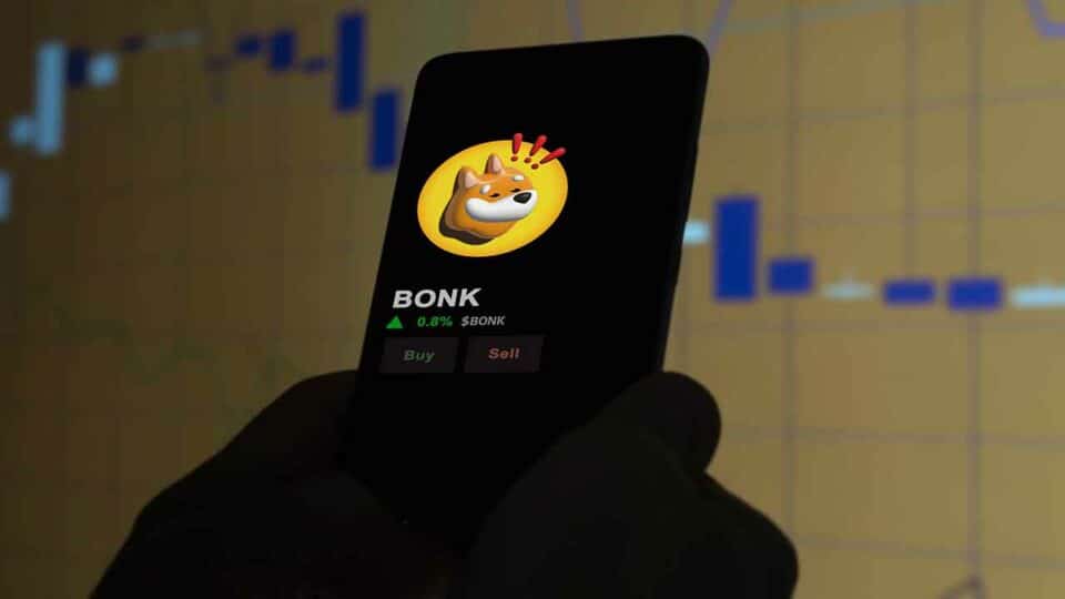 BONK Logo auf Smartphone in Trading App mit Candlestick Chart im Hintergrund