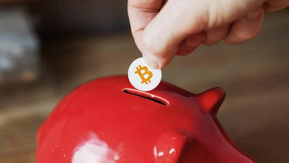 Bitcoin Münze wird in Sparschwein geworfen