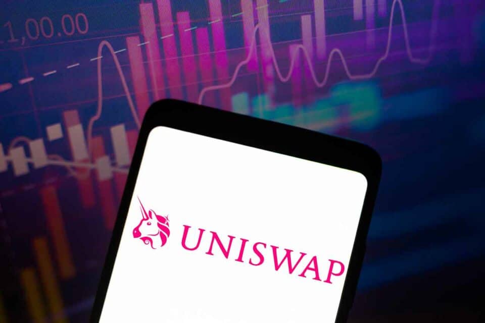 Uniswap Logo auf Smartphone mit Trading-Charts im Hintergrund