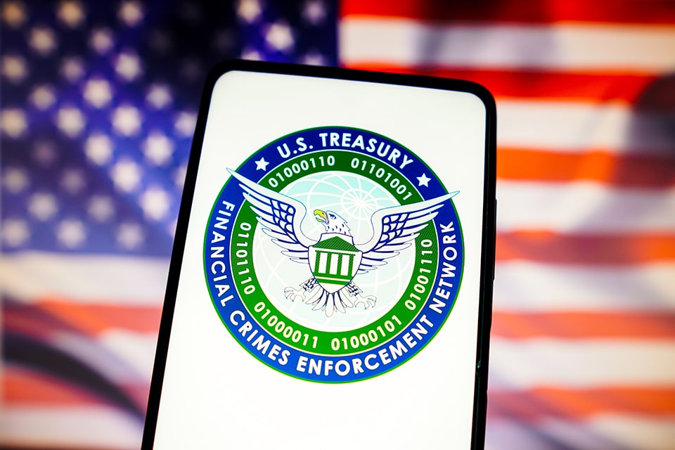 FinCEN Logo auf Smartphone vor einer US-Flagge