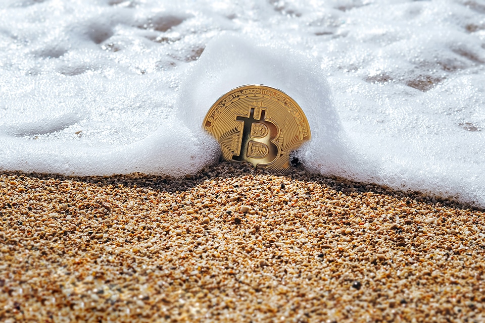 Bitcoin Münze am Strand in einer Welle